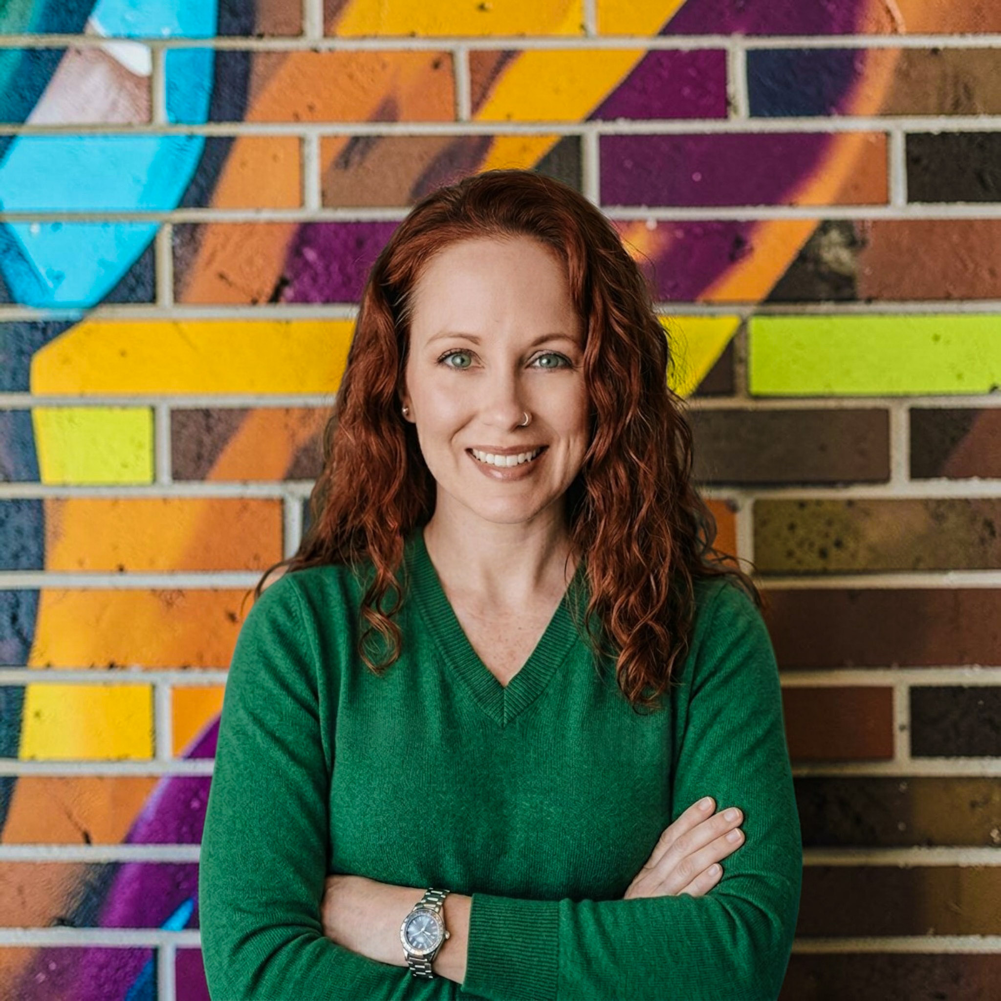 Crystal DeTemple McNeel headshot standing outside with smile in front of a brightly painted brick wall