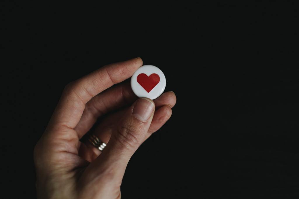 photograph image of  a hand holding a small heart shaped bead